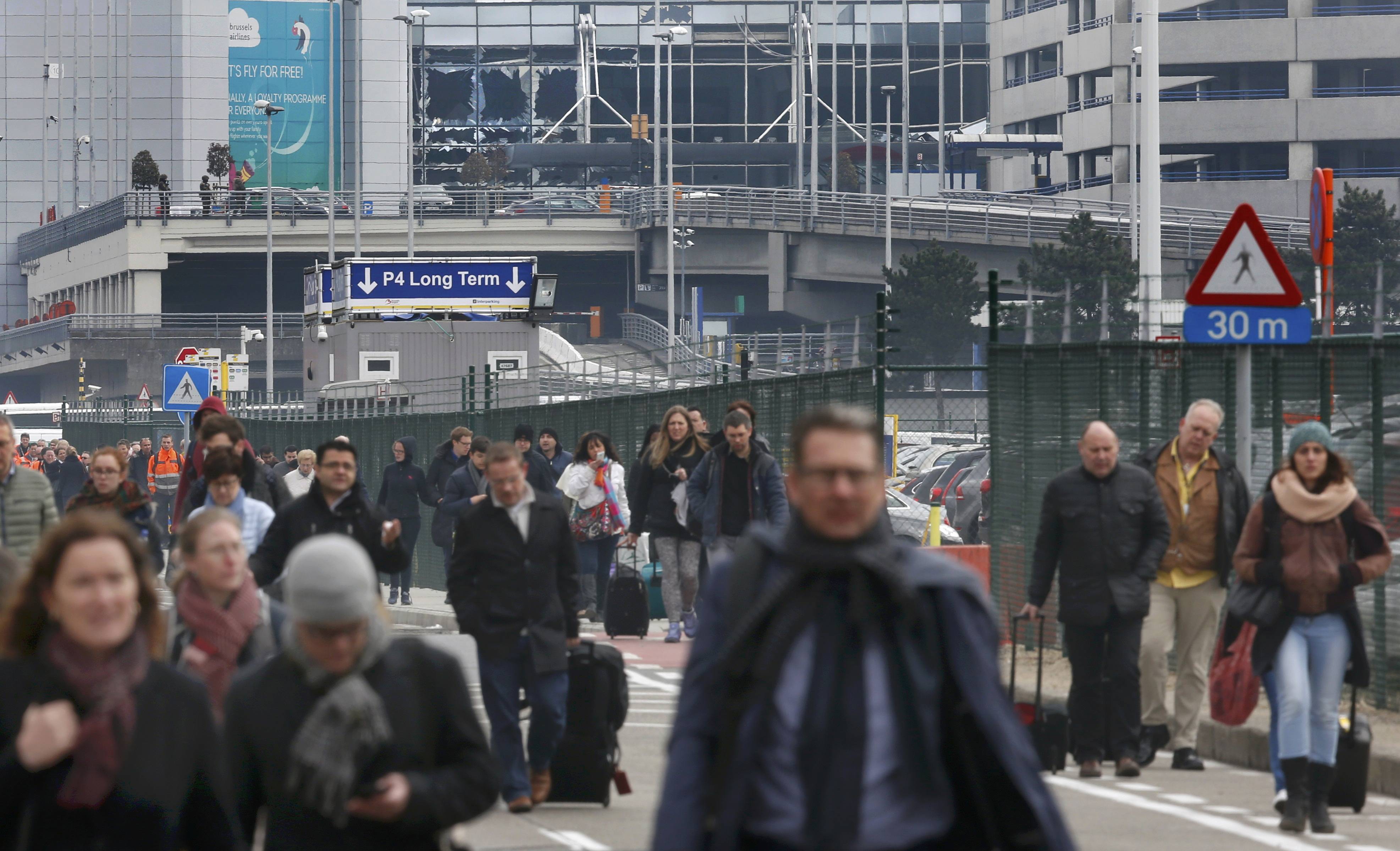 People leave the scene of explosions at Zaventem airport near Brussels, Belgium
